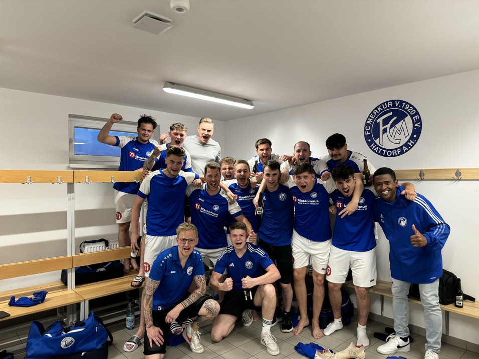 Gruppe junger Fu&szlig;ballspieler in blauen Trikots feiern ausgelassen in einem Umkleideraum.